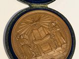 une médaille d'or dans un écrin bleu posé sur une surface blanche