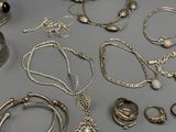 many different types of silver jewelry on a table