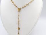 a close up of a necklace with a cross on a mannequin