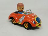 a red toy car with a boy in it on a white surface