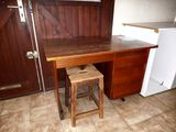 a wooden desk with a stool in front of it