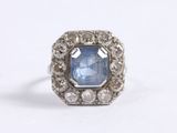 a close up of a ring with a blue stone surrounded by white diamonds