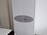 a white cabinet in the corner of a room next to a white table