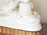 a figurine of a woman laying on top of a pedestal