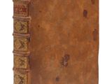 un vieux livre à la couverture brune posé sur une surface blanche