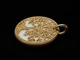 a close up of a gold plated tree of life pendant on a black background