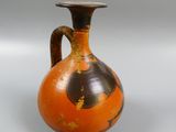 an orange and black vase with a handle on a white background
