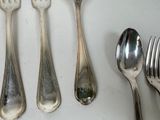 five silver spoons and two silver spoons on a table