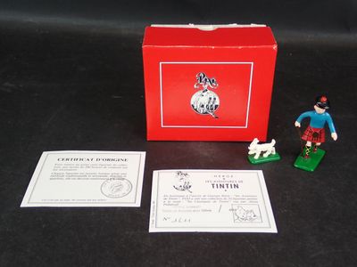 une petite figurine représentant un homme avec un chien devant une boîte rouge