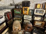 many old radio ' s stacked up in a room