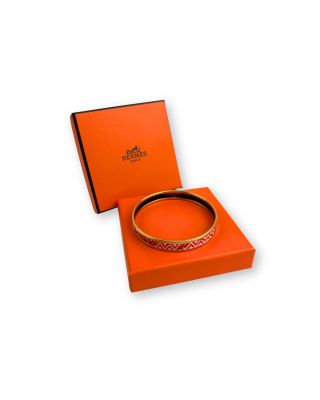 une boîte orange contenant un bracelet, posée sur une surface blanche