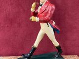 figurine représentant un homme vêtu d'une veste rouge et d'un pantalon blanc, tenant une batte de baseball