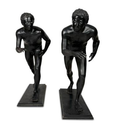 two statues of a man and a woman are standing on a black base