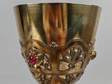a gold goblet with a red stone in it