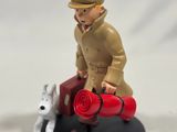 a figurine of a man sitting on a suitcase with a dog
