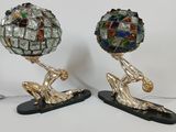 two sculptures of a man holding a ball on top of each other