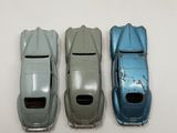 three toy cars sitting side by side on a white surface