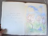 Quelqu'un tient un livre sur lequel figure le dessin d'une personne assise sous un arbre.