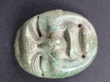 a close up of a green stone mask on a black surface