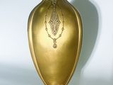a gold vase that is sitting on a white surface