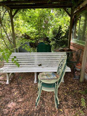 un banc blanc et une chaise verte sous une pergola