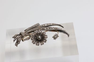 silver plated broochle with flowers and leaves on a clear surface