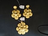 deux paires de boucles d'oreilles en or, munies d'étiquettes, posées sur un fond noir