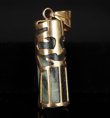 un gros plan d'un pendentif doré et vert sur un fond noir