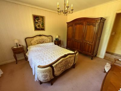 a bedroom with a bed, dresser, and a chandelier