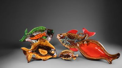 trois figurines de poissons en verre posées les unes à côté des autres sur une surface grise