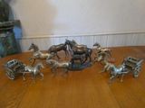 un ensemble de figurines en argent représentant des chevaux et des calèches, posées sur une table
