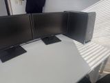 trois écrans d'ordinateur posés sur un bureau blanc