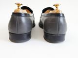 the back of a pair of black leather shoes on a white surface
