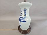 a blue and white vase with a lamp on top of it