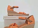 an image of a pair of orange wedged sandals on top of a box