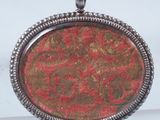 a close up of a pendant with a red and green design on it