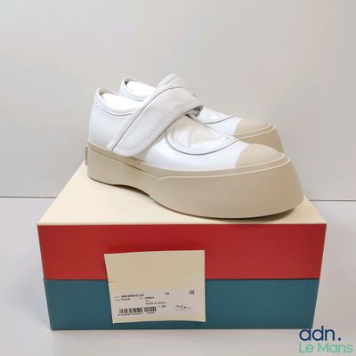 the white shoes are sitting on top of a box on a white surface