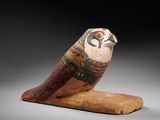 an egyptian figurine of a bird on a wooden base