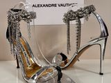 des chaussures à talons hauts argentées ornées de chaînes, avec une carte de visite posée devant