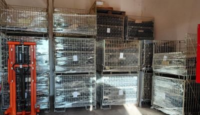 many cages and pallets in a warehouse with a fork lift