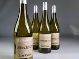 trois bouteilles de vin blanc sont alignées sur une table