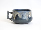 a blue cup with a handle on a white surface