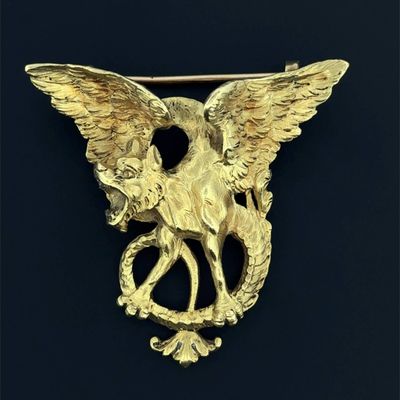un gros plan d'une broche en or ornée d'un aigle