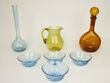 plusieurs vases et bols en verre de différentes couleurs posés sur une surface blanche