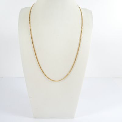 a gold chain necklace on a mannequin head