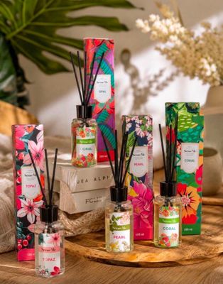 an assortment of reeds and candles on a table with flowers