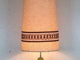 a green table lamp with a beige shade on top of it