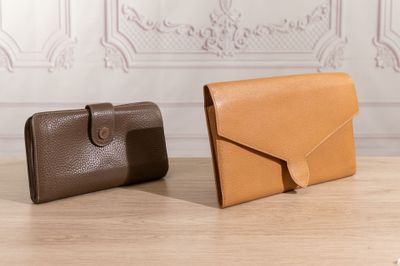 two leather wallets sitting on top of a table next to each other