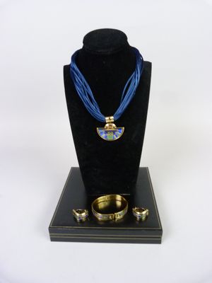 necklace, bracelet, and ring set on display on a black stand
