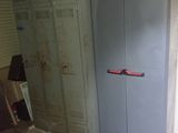 une armoire bleue dans un coin de la pièce, avec une poignée rouge